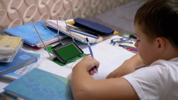 Školák Levák Píše s perem v zápisníku Má domácí úkol používat Smartphone — Stock video