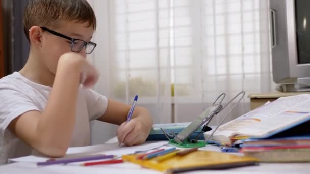 Αγόρι με γυαλιά γράφει με στυλό σε σημειωματάριο, αγγίζει Smartphone με δάχτυλα — Αρχείο Βίντεο