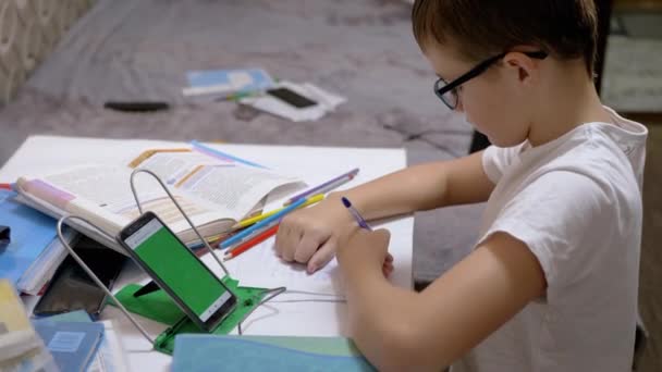 Schüler mit Brille schreibt mit Stift in Notizbuch — Stockvideo