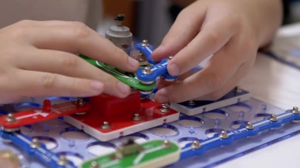 Curious Boy Assembles Electrical Circuit of Metal Construction Kit Parts. Zoom — Stock Video