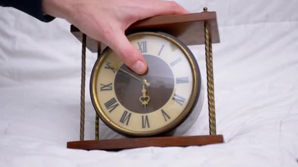 La mano masculina sostiene el reloj de mesa de madera clásico vintage con números romanos. 4K — Vídeo de stock