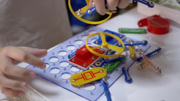 Kíváncsi fiú játszik egy elektromos fém konstruktor az asztalon otthon. 180fps — Stock videók