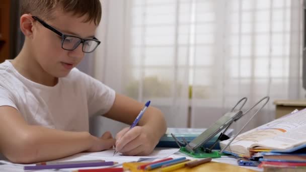 Gözlüklü Gülümseyen Öğrenci Not Defterinde Kalemle Yazar, Akıllı Telefonla Konuşur — Stok video