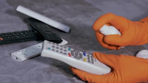 Руки женщины в резиновых перчатках Телевизор пульт дистанционного управления с Хлопчатобумажной площадкой и спрей — стоковое видео