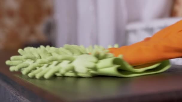 Mano femminile in gomma arancione guanti pulisce una superficie di legno con microfibra Rag — Video Stock