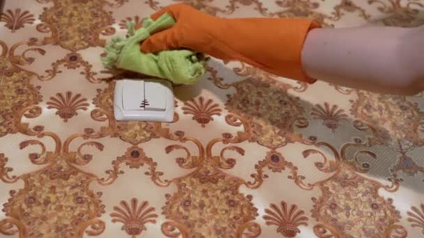 Vrouwelijke handen in oranje rubberen handschoenen Veegt licht schakelaar thuis — Stockvideo