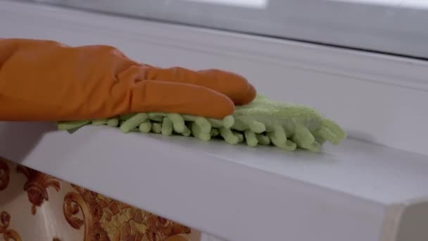 Dámské ruce v oranžové gumové rukavice utírá prach z okenního parapetu tkaniny doma — Stock video
