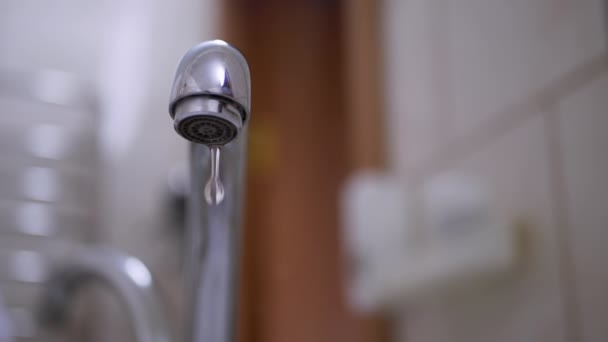 Gotas de agua fluyen lentamente hacia abajo, caen en el fregadero del grifo. Fuga. En cámara lenta. — Vídeo de stock