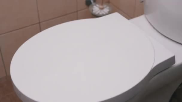 Female Hand met un rouleau de papier toilette sur le couvercle blanc des toilettes. 4K — Video