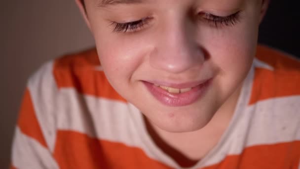 Niño sonriente con bonitas pestañas gruesas y largas abre y cierra los ojos. Mira hacia abajo — Vídeo de stock