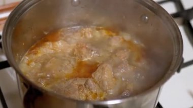 Domates sosunda, bir tencerede domuz eti parçaları kaynıyor. Domates sosunda gaz ocağında. Büyüt