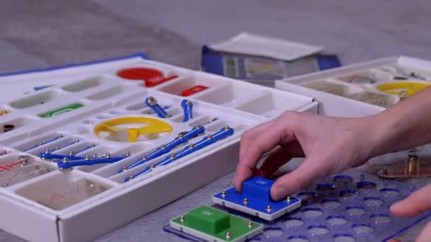 Teen Girl Hands собирает электрическую цепь металлических конструкционных деталей — стоковое видео