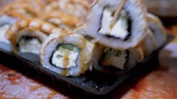 竹棒付き寿司マスターは、プラスチック製の箱に寿司ロールを広げます。4K — ストック動画