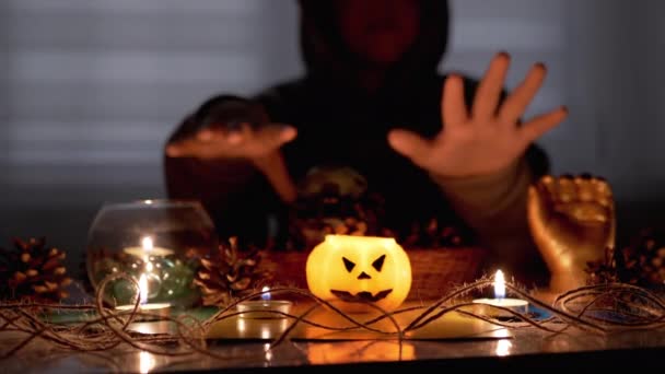Мальчик-шаман в хорошем настроении совершает обряд при свече в темной комнате на Хэллоуин — стоковое видео