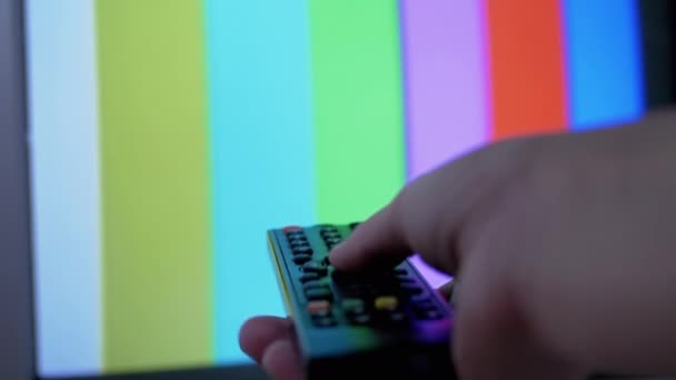 Женская рука с помощью ТВ пульт дистанционного управления пытается переключатель SMPTE Цвет баров тестовый шаблон — стоковое видео