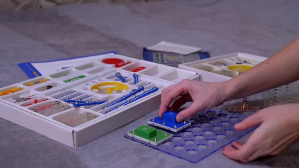 Teenager-Mädchenhände bauen einen elektrischen Schaltkreis aus Metallbauteilen zusammen — Stockvideo