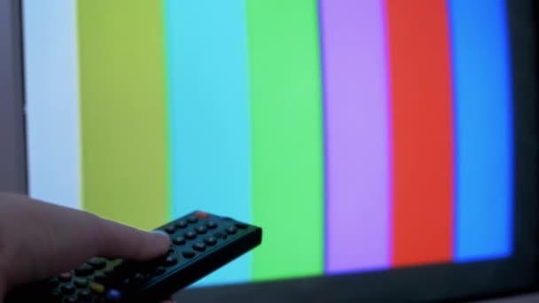 Weibliche Hand mit TV-Fernbedienung versucht einen Schalter SMPTE Farbbalken Testmuster — Stockvideo