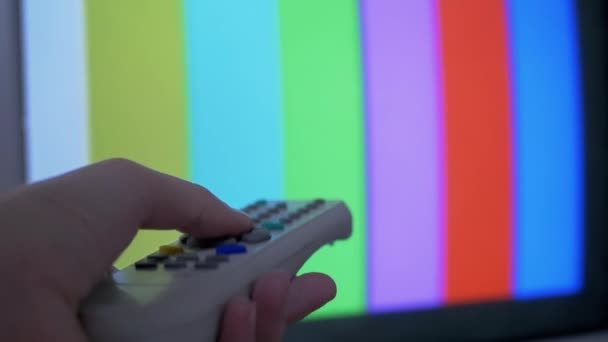 Женская рука с помощью ТВ пульт дистанционного управления пытается переключатель SMPTE Цвет баров тестовый шаблон — стоковое видео