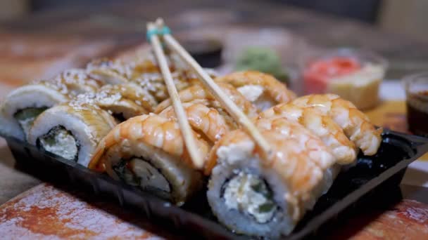 Rotoli di sushi giapponese in scatola di plastica un servito sul tavolo con bastoncini di bambù, Wasabi — Video Stock
