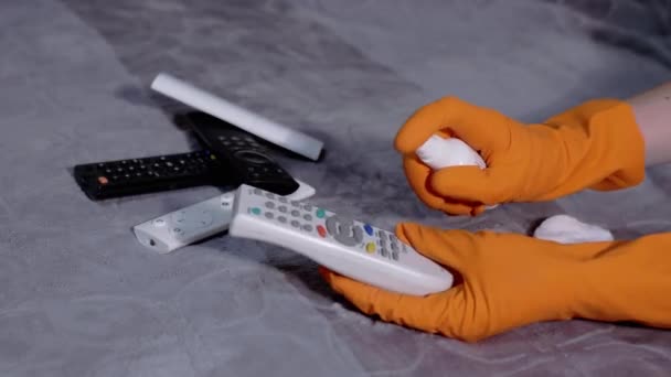 Vrouwelijke handen in Rubber Handschoenen Veegt TV afstandsbediening met katoenen pad en spray — Stockvideo