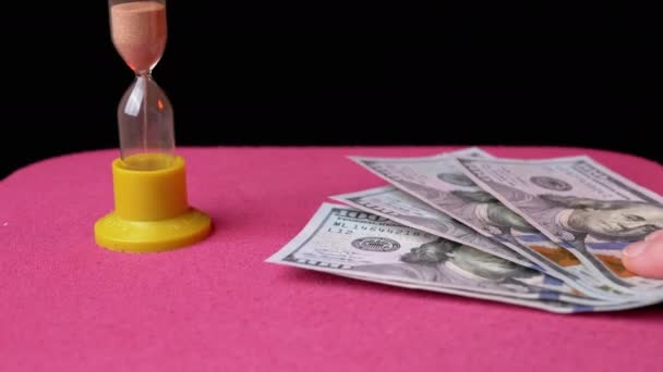 Sprid många 100 amerikanska dollar på bordet med timglas. Ge bort skulden i tid — Stockvideo