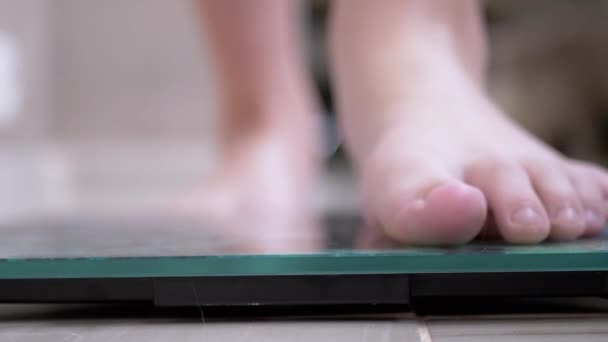 Εφηβικό παιδί σε κλίμακες Μετρήστε το βάρος. Το παιδί ελέγχει το βάρος του ξυπόλητος. 4K — Αρχείο Βίντεο