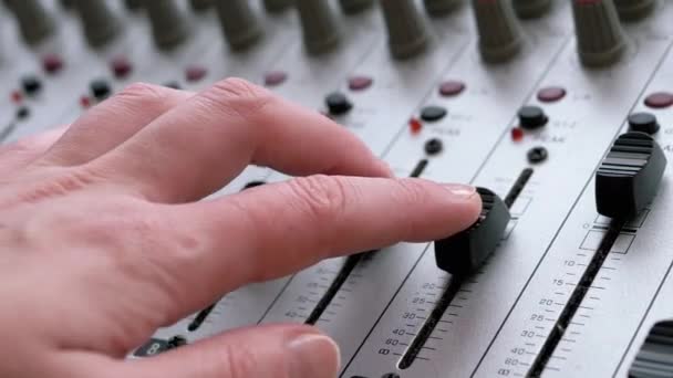 Sound Engineer, DJ beweegt schuifregelaars met vingers op audio mixer in de opnamestudio — Stockvideo