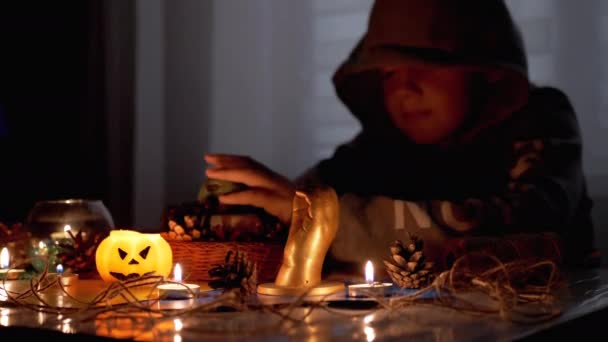 Misterioso ragazzo con in cappuccio gioca con ragno da candela in camera oscura su halloween — Video Stock
