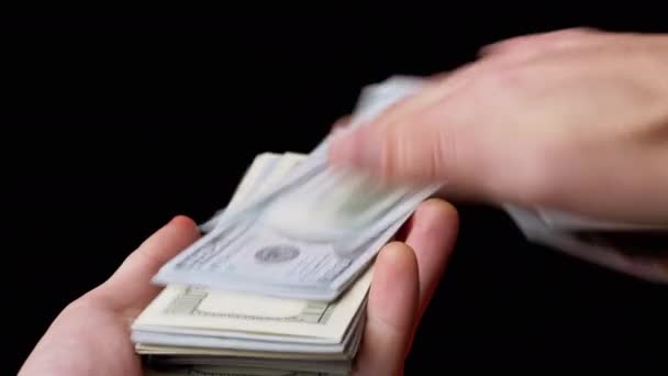 Mains masculines Scatter pile de 100 projets de loi en dollars américains sur fond noir. De l'argent. 4K — Video