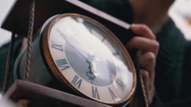 Mãos femininas mantém o relógio de mesa de madeira clássico vintage com numerais romanos. 4K — Vídeo de Stock
