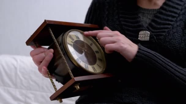 Mãos femininas mantém o relógio de mesa de madeira clássico vintage com numerais romanos. 4K — Vídeo de Stock