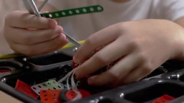 Meraklı Çocuk Evdeki Masa 'da Yapıcı Metal Parçaları ile oynuyor. Büyüt