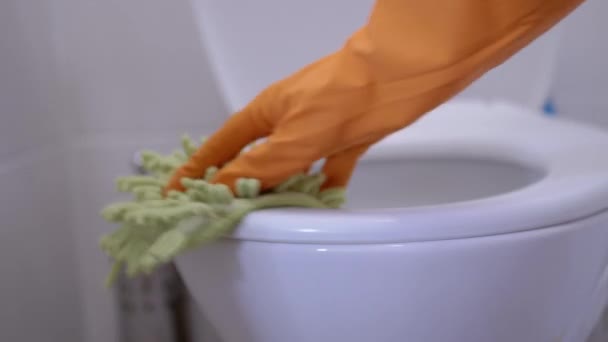 Las manos femeninas en guantes de goma naranja LavarTapa del inodoro con paño verde, trapo — Vídeos de Stock