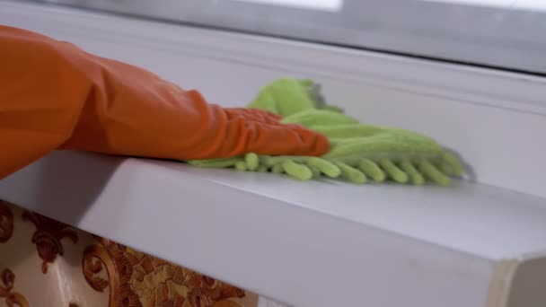 Mãos femininas em luvas de borracha laranja limpa o pó do peitoril da janela um pano em casa — Vídeo de Stock