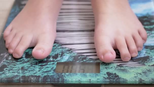 スケールで10代の子供は重量を測定します。子供は彼の重量裸足をチェックします。ズーム — ストック動画