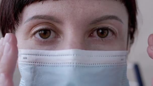 Fiatal lány maszkban forgatja a vörös, véreres szemeket. Vírusos kötőhártya-gyulladás. 4K — Stock videók