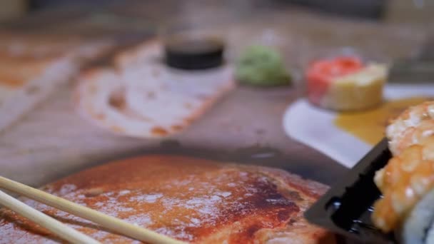 I rotoli di sushi giapponesi in scatola di plastica sono serviti al tavolo del ristorante. 4K. Primo piano — Video Stock