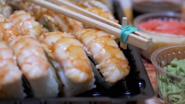 Rouleaux de sushi japonais dans une boîte en plastique a servi sur la table avec des bâtons de bambou, Wasabi — Video