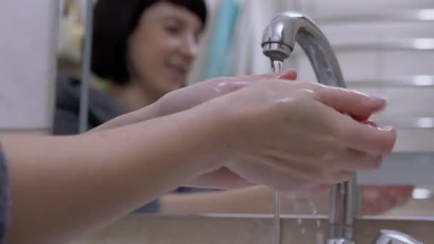 La donna accende il rubinetto dell'acqua e lava il sapone liquido delle mani con schiuma. Sfocatura. 4K — Video Stock
