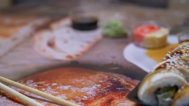 A japán sushi tekercsek műanyag dobozban kerülnek felszolgálásra az étterem asztalánál. 4K. Közelkép — Stock videók