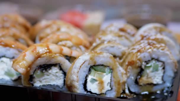 A bambuszpálcikás sushi mester egy műanyag dobozba teríti a sushi tekercseket. Nagyítás — Stock videók