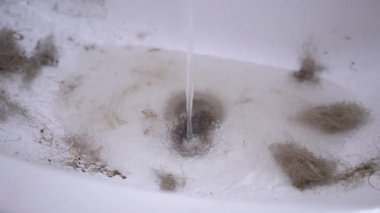 Su musluğundan akan su lavaboya akıyor. Saç, yün, çöp ile tıkanmış.