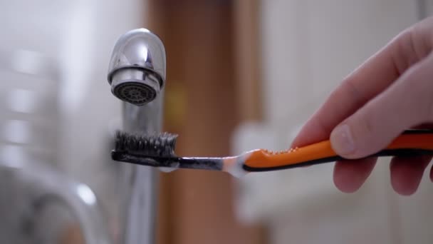 Gocce d'acqua dal rubinetto cadono lentamente sullo spazzolino da denti a setole nere. Rallentatore — Video Stock