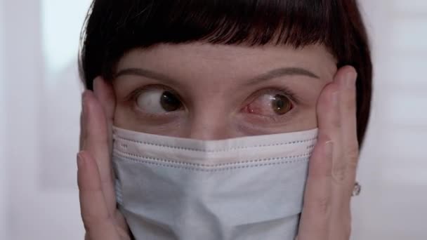 Fiatal nő maszkban forgatja a vörös, véreres szemeket. Vírusos kötőhártya-gyulladás. 4K — Stock videók