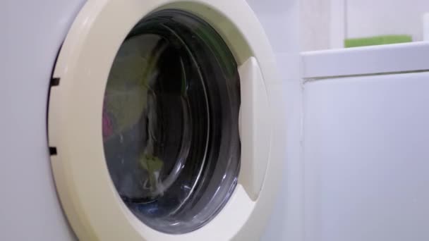 Waskleurige kleding in de huishoudelijke wasmachine. Draaiende trommel. 4K — Stockvideo