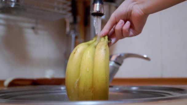 Lavados femeninos maduros, plátanos amarillos con chorro de agua corriente de grifo en la cocina — Vídeo de stock