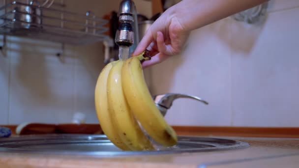 Kvinnliga tvättar mogna, gula bananer med ström rinnande vatten från kranen i köket — Stockvideo