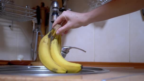 Lavados femeninos maduros, plátanos amarillos con chorro de agua corriente de grifo en la cocina — Vídeo de stock