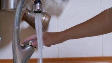 Kadın güçlü bir akarsu deresinin altında ellerini yıkar, musluğu kapatır. Sızıntı. 4K