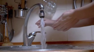 Kadın güçlü bir akarsu deresinin altında ellerini yıkar, musluğu kapatır. Sızıntı.